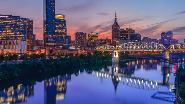 The Nashville skyline and Cumberland River lit up at dusk